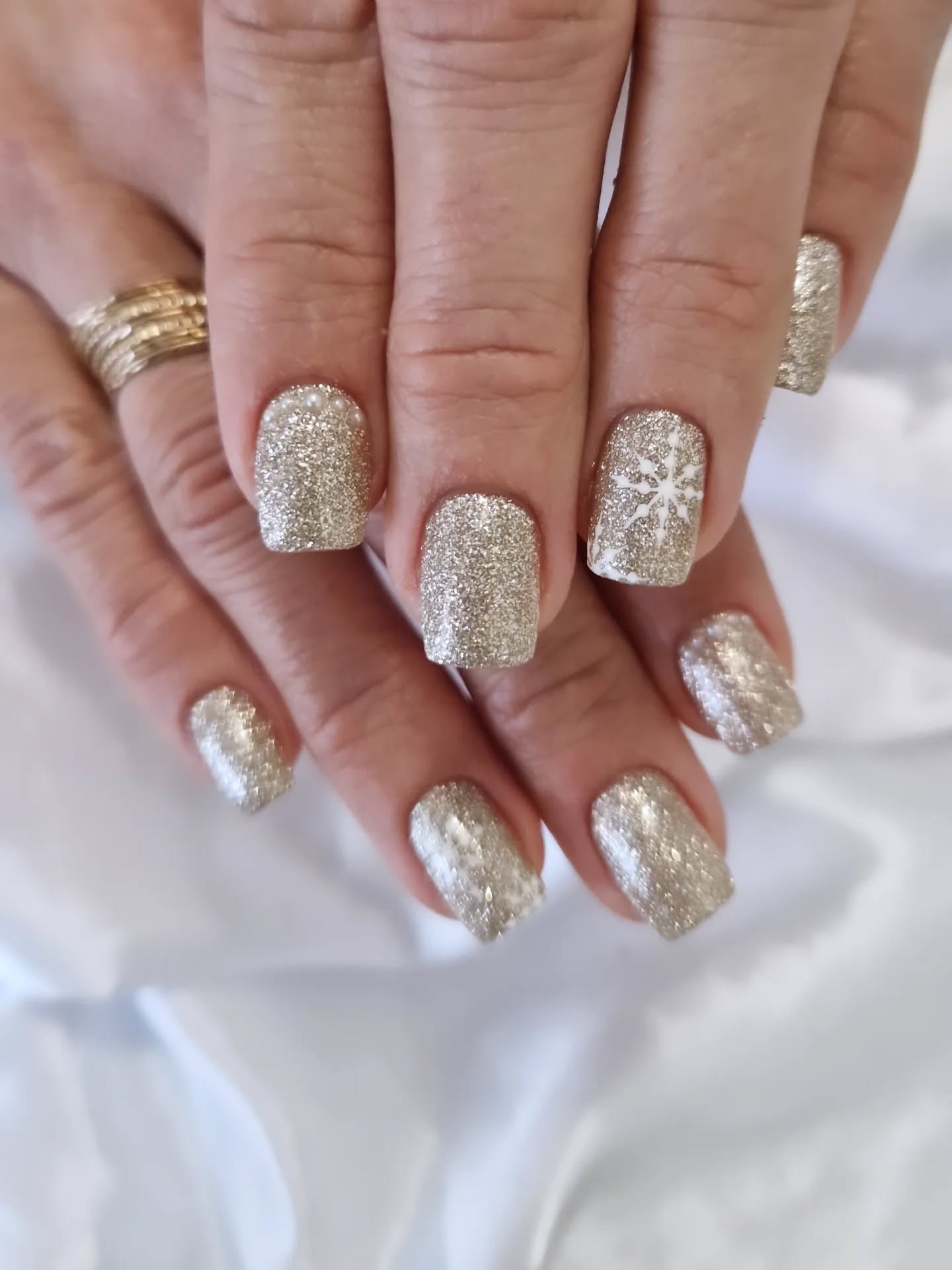 Ongles courts pailletés champagne, perles et flocon